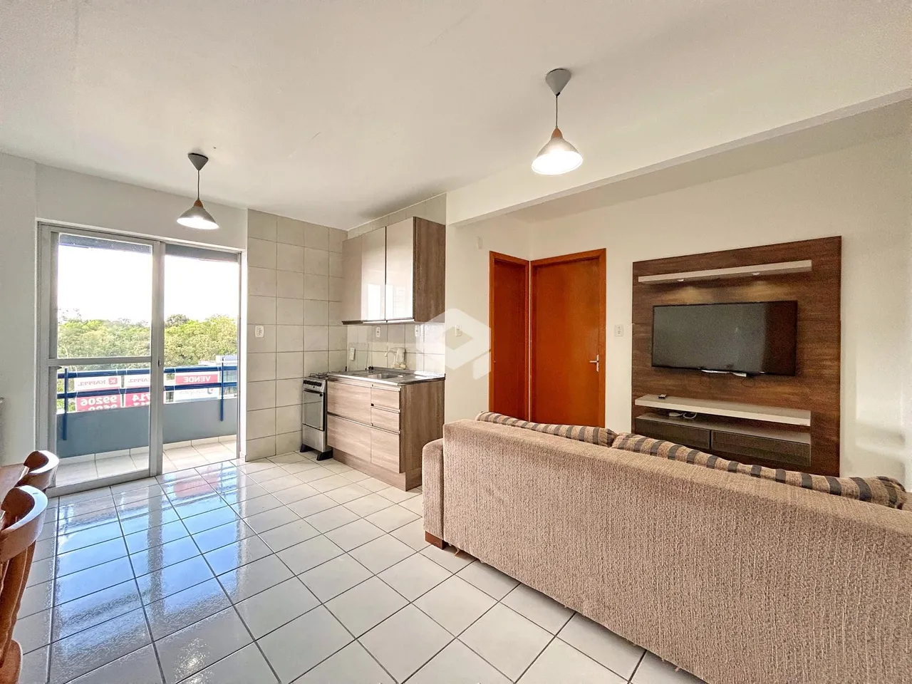 Sala de estar e cozinha com piso de cerâmica e portas de vidro que dão para o exterior.