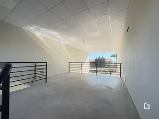 Vista de um espaço interno com teto inclinado e piso de concreto.