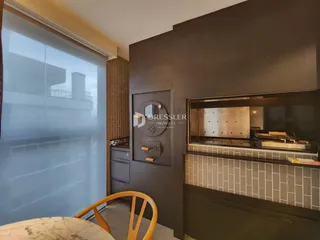Interior de uma cozinha moderna com armários escuros e revestimento de azulejos claros.