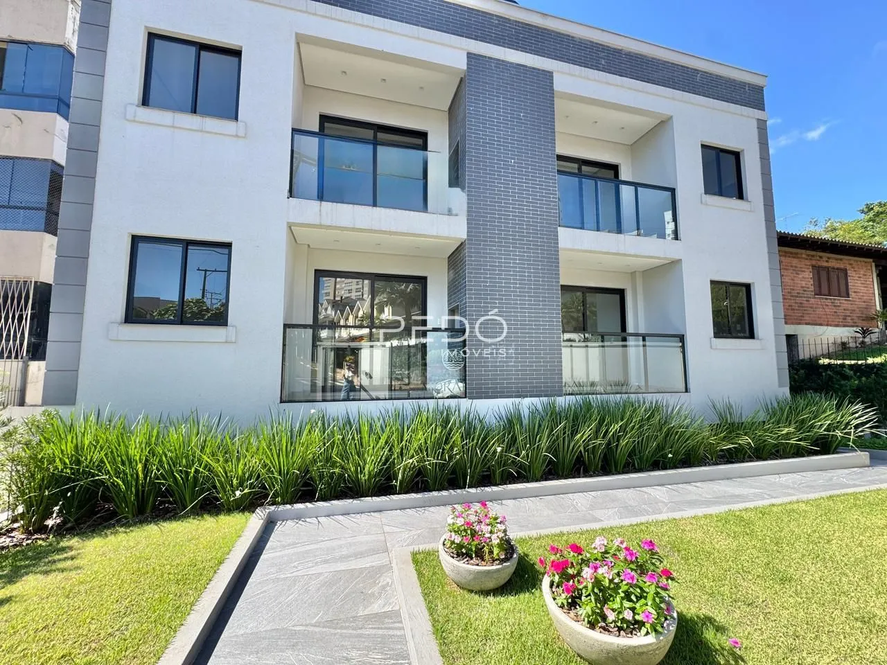 Fachada de um prédio residencial moderno em Lajeado, Brasil, com jardim frontal.