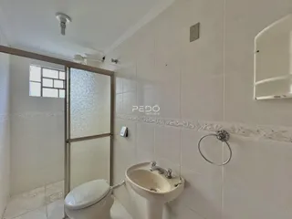 Foto de um banheiro com revestimento cerâmico e box de vidro.