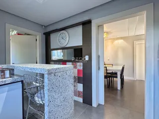 Vista da cozinha com ilha de granito e passagem para outra área da casa.