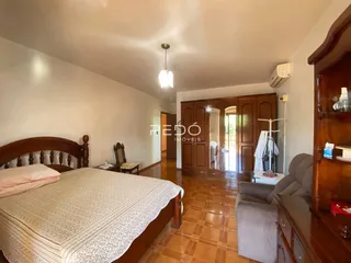 Quarto com cama de madeira e piso de cerâmica em uma residência.