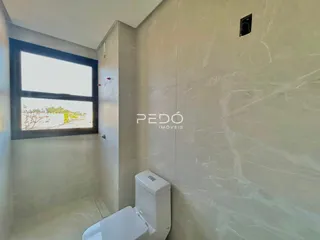 Banheiro com paredes em mármore claro e janela.