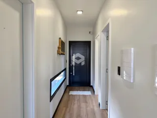 Corredor interno de uma residência com piso de madeira.