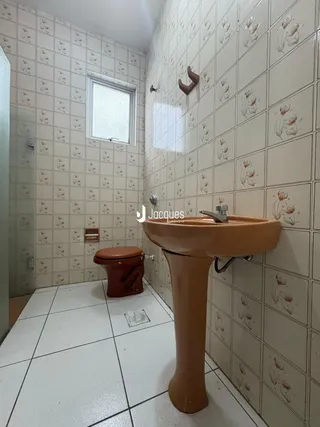 Foto de um banheiro com azulejos brancos e louças de cor marrom.