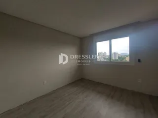 Ambiente interno de uma sala com piso de madeira e janela.