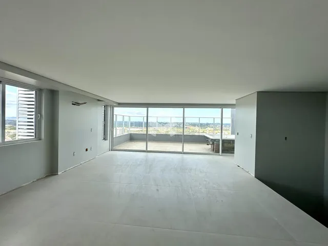 Ambiente interno de uma sala ampla com vista para a paisagem.