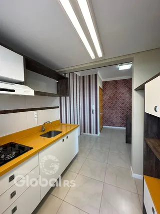 Cozinha com armários brancos e bancadas amarelas em um imóvel no Brasil.