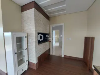 Interior de uma sala com piso de madeira e parede de destaque em Lajeado.