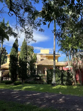 Fachada de uma residência em Lajeado, Brasil, cercada por árvores e gramado.