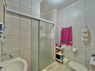 Um banheiro com revestimento cerâmico e box de vidro.