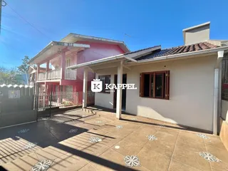 Fachada de uma residência com pátio externo pavimentado com cerâmica sob luz do dia.