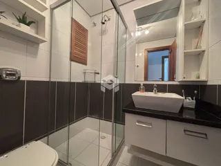Interior de um banheiro com box de vidro e bancada moderna.