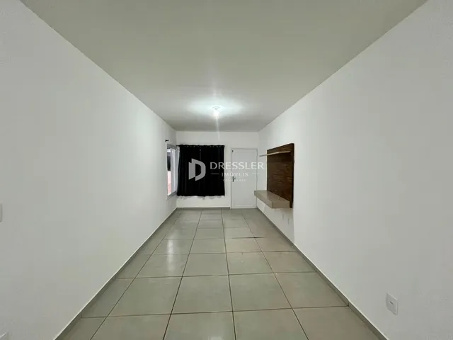 Corredor interno de uma residência com paredes brancas e piso de cerâmica.