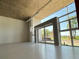 Ambiente interno amplo com grandes janelas de vidro e teto de concreto.