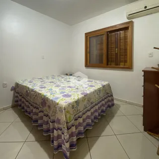 Quarto com cama e piso de cerâmica em uma residência.