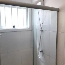 Foto de um box de banheiro com revestimento cerâmico e vidro.