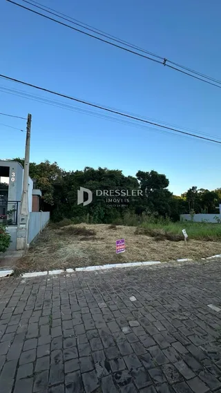 Vista externa de um terreno com pavimento de tijolos na frente da propriedade.