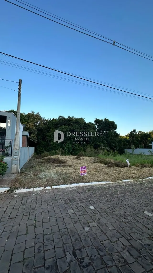 Vista externa de um terreno com pavimento de tijolos na frente da propriedade.