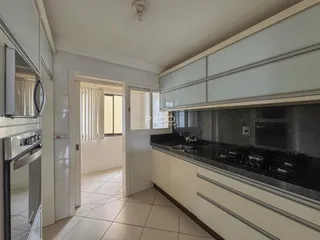 Cozinha com armários brancos e bancada escura em um imóvel no Brasil.