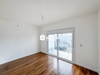 Uma sala de estar com piso de madeira e porta de vidro que dá para o exterior.