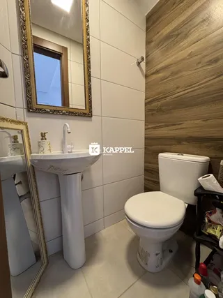 Banheiro com pia de pedestal e vaso sanitário em um ambiente com revestimento de madeira.