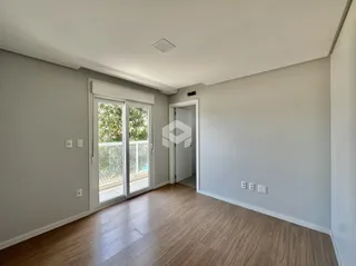 Sala de estar com piso de madeira e portas de vidro que dão acesso ao exterior.