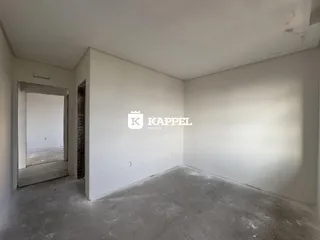 Foto de um cômodo vazio com paredes brancas e piso de concreto.