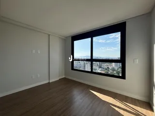 Sala com piso de madeira e grande janela com vista da cidade.