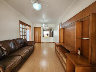 Sala de estar com sofá de couro marrom e piso de madeira clara.