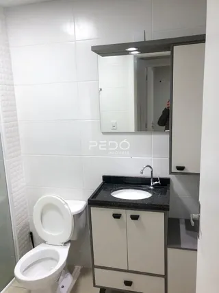 Foto de um banheiro com azulejos brancos e louças sanitárias modernas.