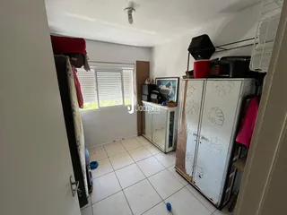 Interior de um cômodo com piso de cerâmica e armário branco.