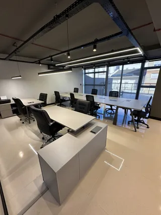 Ambiente de escritório moderno com mesas longas e cadeiras de trabalho.