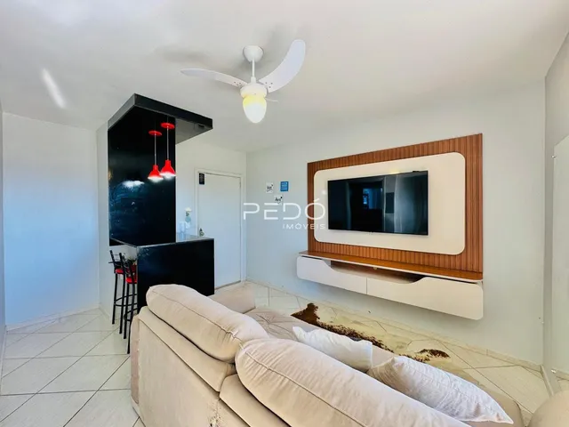 Sala de estar com sofá e painel de TV em um apartamento em Lajeado.