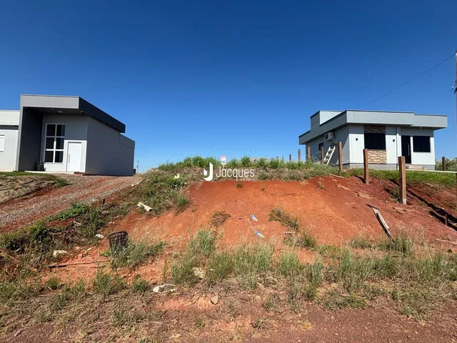 Fachada de duas construções em terreno com solo exposto.