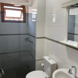 Foto de um banheiro com revestimento de azulejos brancos e box de vidro.