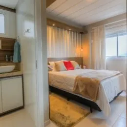 Quarto com cama e cortinas claras em um imóvel.