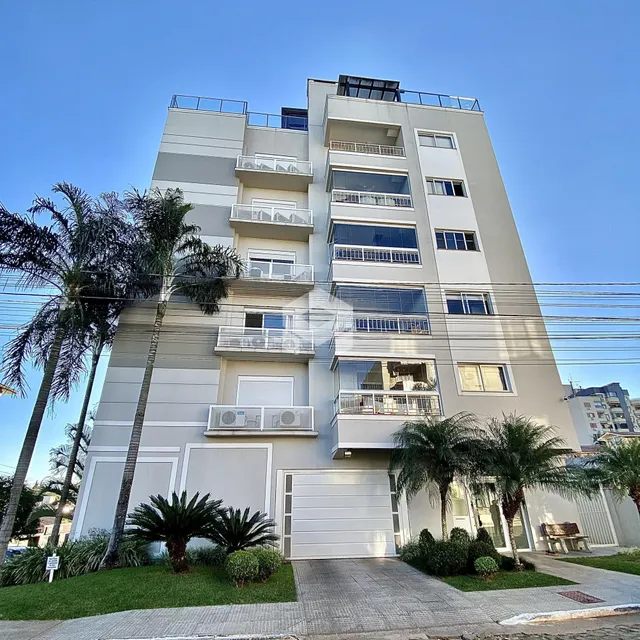 Fachada de um prédio residencial em Lajeado, Brasil, com palmeiras no primeiro plano.
