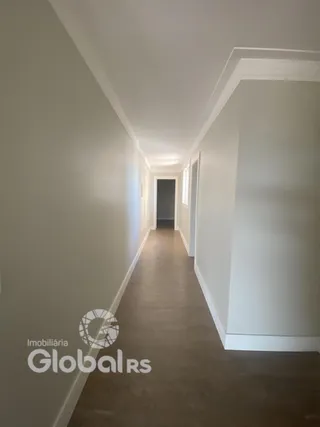 Corredor interno de uma residência com paredes brancas e piso de madeira.