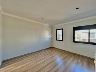 Sala de estar com piso de madeira clara e paredes brancas.