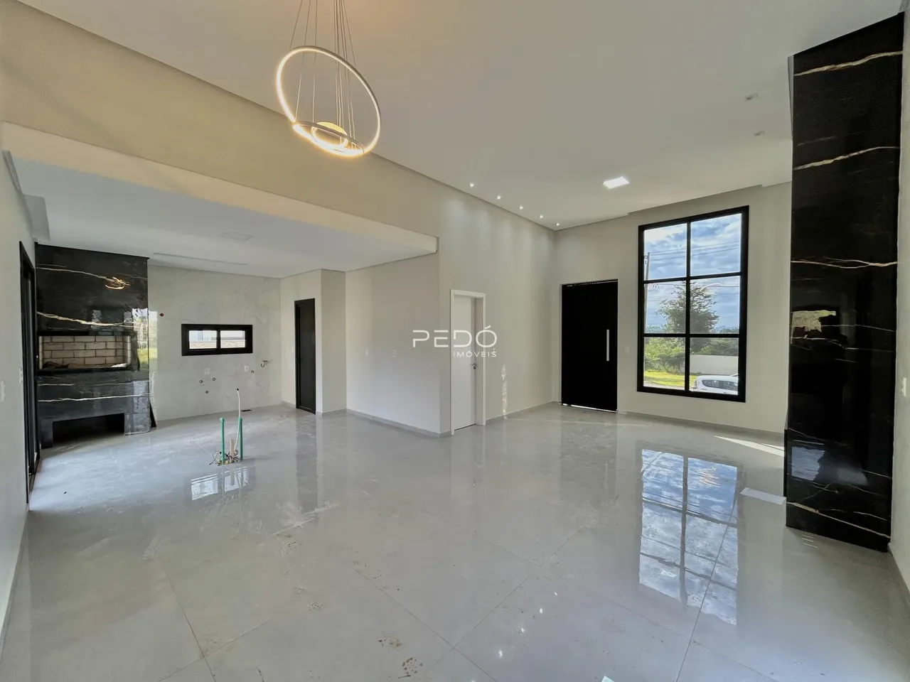 Ambiente interno de uma sala ampla com piso claro e paredes brancas.