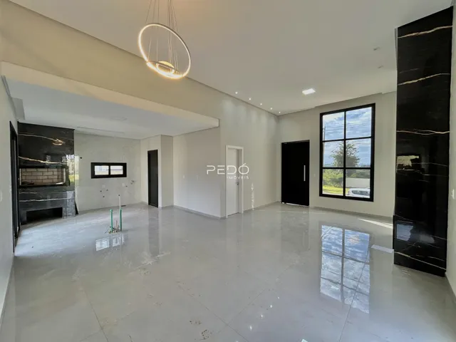 Ambiente interno de uma sala ampla com piso claro e paredes brancas.