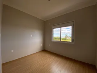Foto interna de um cômodo com piso de madeira e uma grande janela com vista.
