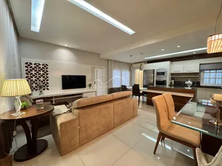 Sala de estar moderna com sofá grande e área de cozinha integrada.
