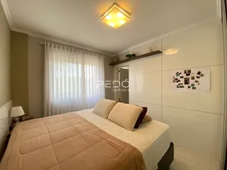 Quarto com cama e cortinas brancas em um imóvel.