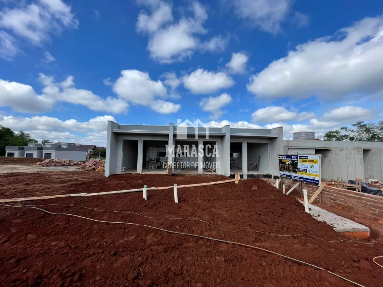 Vista externa de uma construção em terreno com solo exposto.