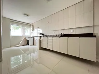 Interior de uma cozinha moderna com armários brancos e piso claro.