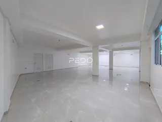Vista interna de um grande espaço vazio com piso de cerâmica claro.