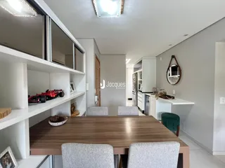 Vista de uma sala de jantar com móveis de madeira e estantes brancas.